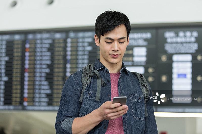 青年男子背着包拿着手机在机场图片素材