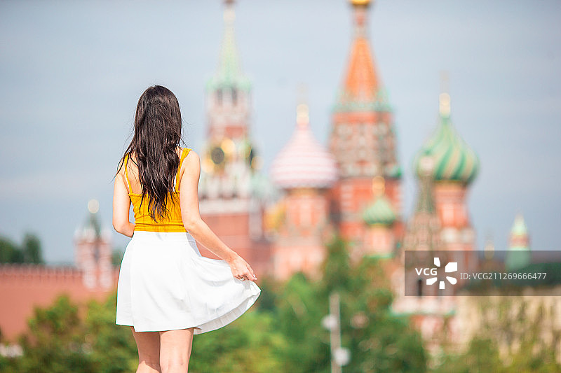 莫斯科红场，一名年轻女子手持裙子，站在圣巴塞尔大教堂前图片素材
