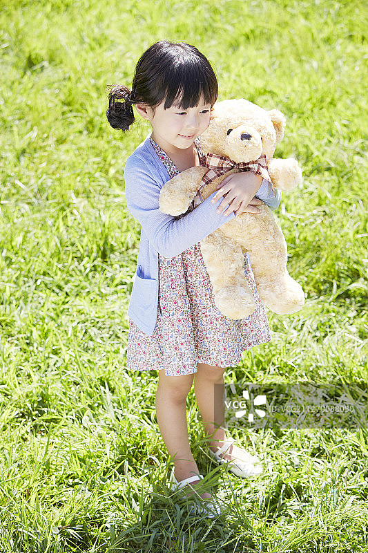小女孩在公园里抱着泰迪熊的照片图片素材