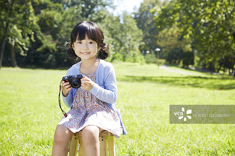 小女孩拿着相机在公园里拍照图片素材