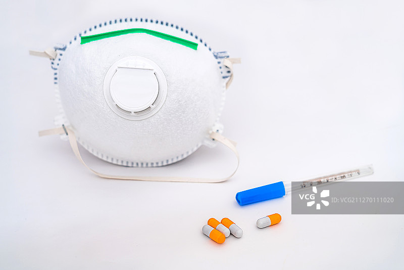 白色背景下的N95口罩、胶囊和体温计图片素材
