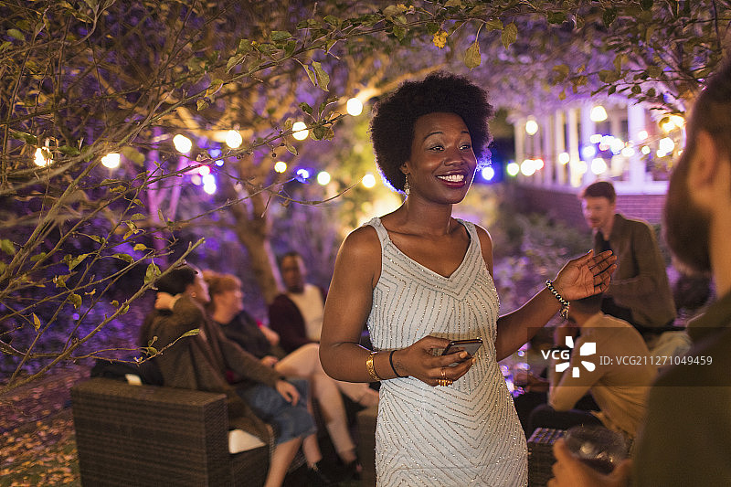 微笑的女人与智能手机与朋友在花园聚会图片素材