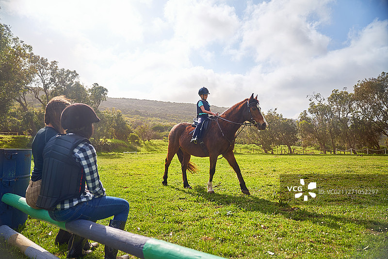 女孩骑马在阳光明媚的草地围场图片素材