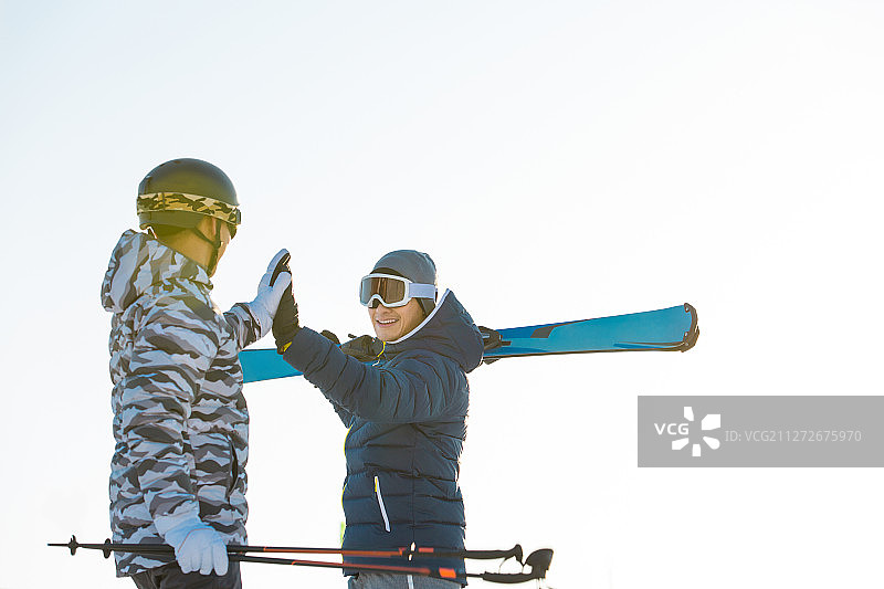 两个青年男子在户外滑雪场击掌庆祝成功图片素材