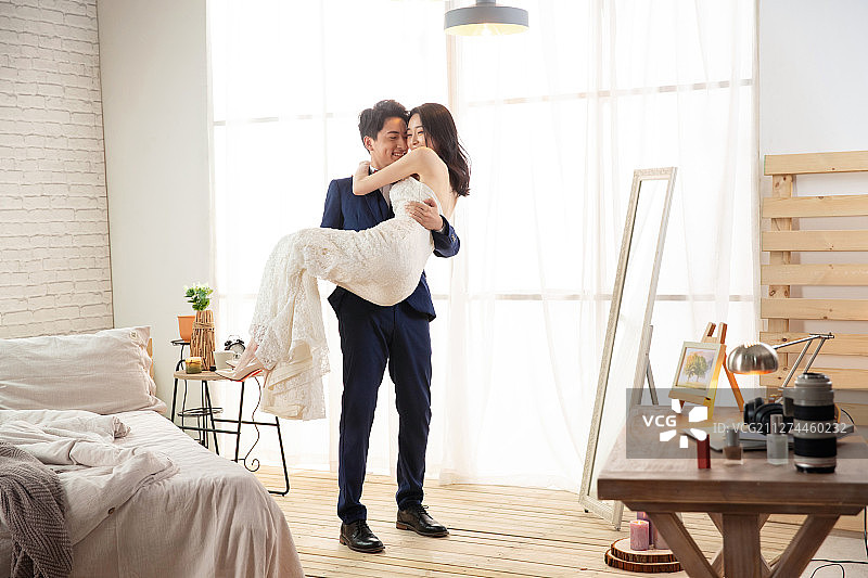 卧室里幸福的丈夫把妻子抱起来图片素材
