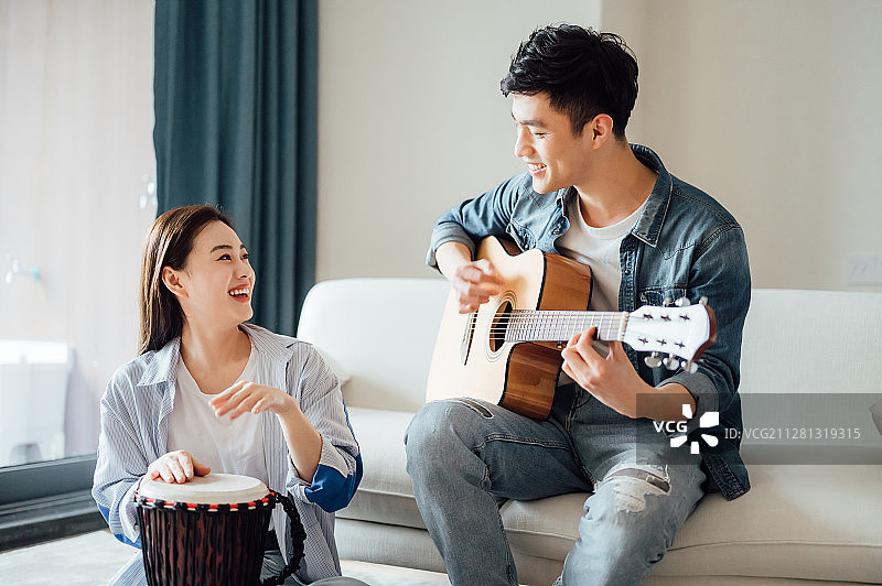 亚洲年轻情侣在家弹琴唱歌图片素材