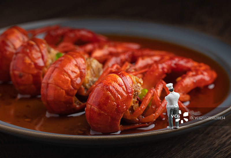 木桌上盘子里的麻辣小龙虾与厨师图片素材