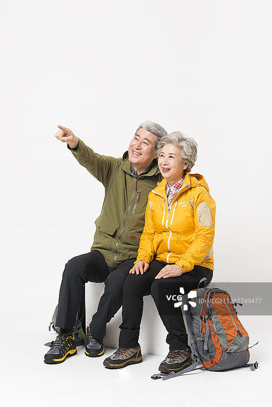 老夫妇的照片穿着攀岩服坐下来指向和看某处图片素材
