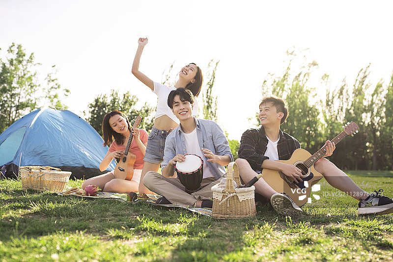 快乐的年轻人在户外野餐演奏音乐图片素材