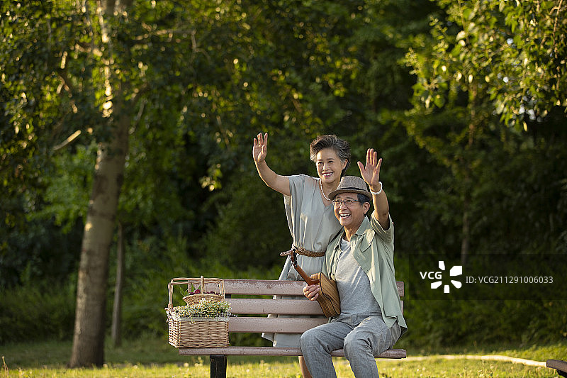 老年夫妻在公园长椅上打招呼肖像图片素材