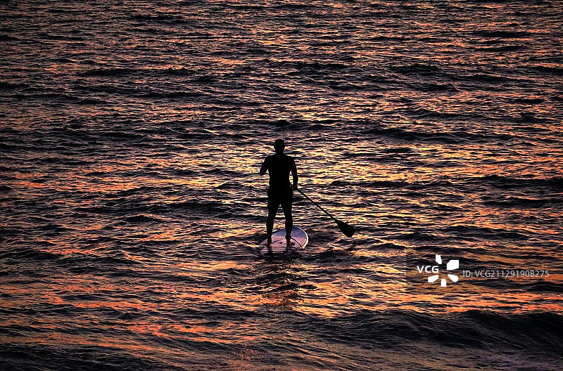 后视镜的剪影的人划桨冲浪在海上日落，马拉加，西班牙图片素材