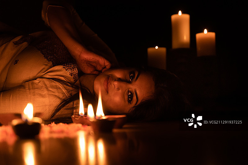 蜡烛照亮下躺在地板上的女人的肖像图片素材