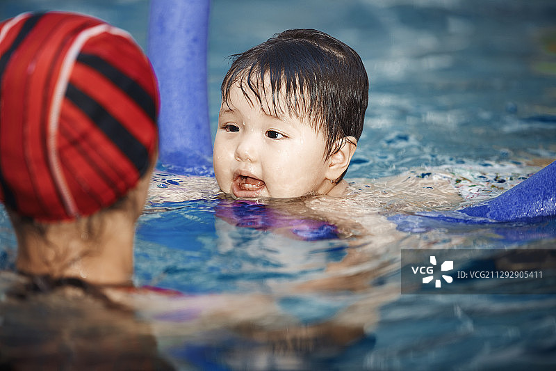 母亲或游泳教练在游泳池教一岁的婴儿图片素材