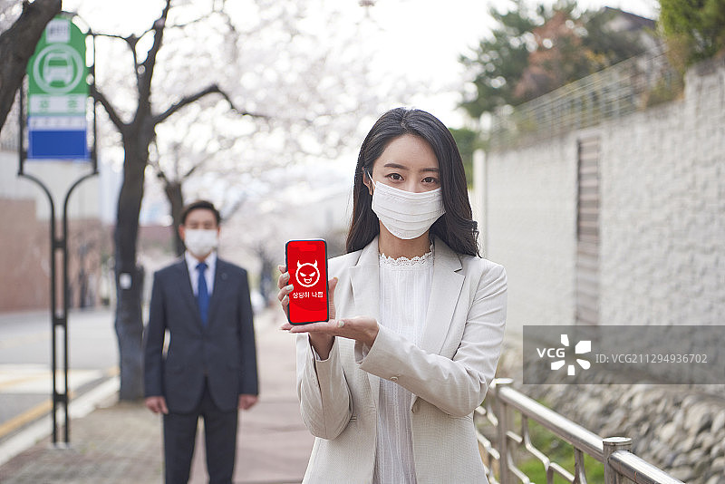 商人和妇女戴着污染口罩，拿着智能手机，显示状况很差图片素材