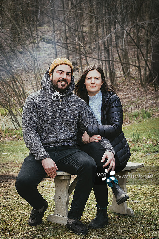 一对微笑的夫妇坐在森林里的长凳上的肖像，Magog，加拿大图片素材