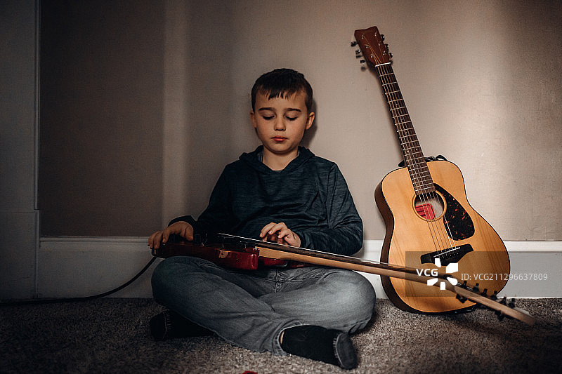 坐在家里地板上弹吉他的男孩，莉娜，美国图片素材