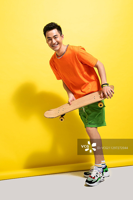 拿着滑板的快乐青年男人图片素材