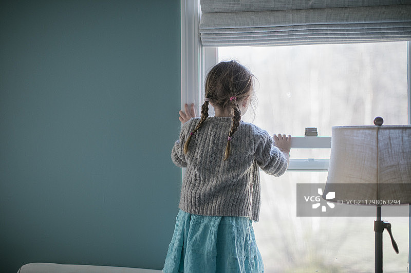 一个小女孩望着窗外的肖像图片素材