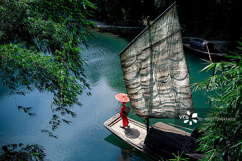 湖北宜昌长江三峡人家龙进溪，传统服装土家少女站在木帆船船头图片素材