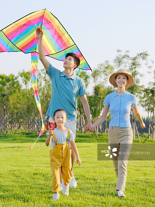 快乐的三口之家在公园放风筝图片素材