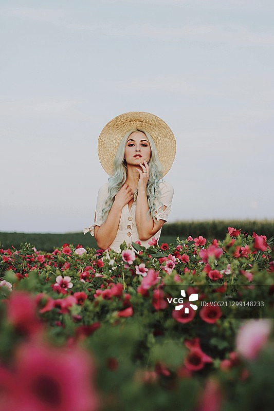 塞尔维亚库尔平，一名年轻女子戴着帽子站在有花的植物中间图片素材