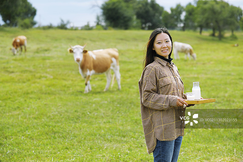 一个东方女人在草原牧场端着牛奶图片素材
