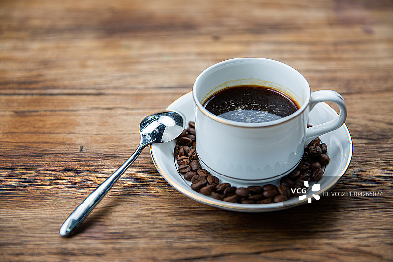 一杯放在木头桌子上的卡布奇诺拿铁美式咖啡与咖啡勺玫瑰图片素材