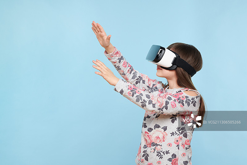 斯洛伐克女孩在蓝色背景下使用虚拟现实模拟器图片素材