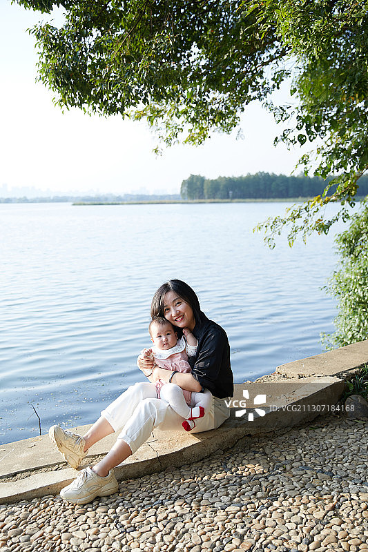 青年妈妈抱着婴儿在湖边图片素材