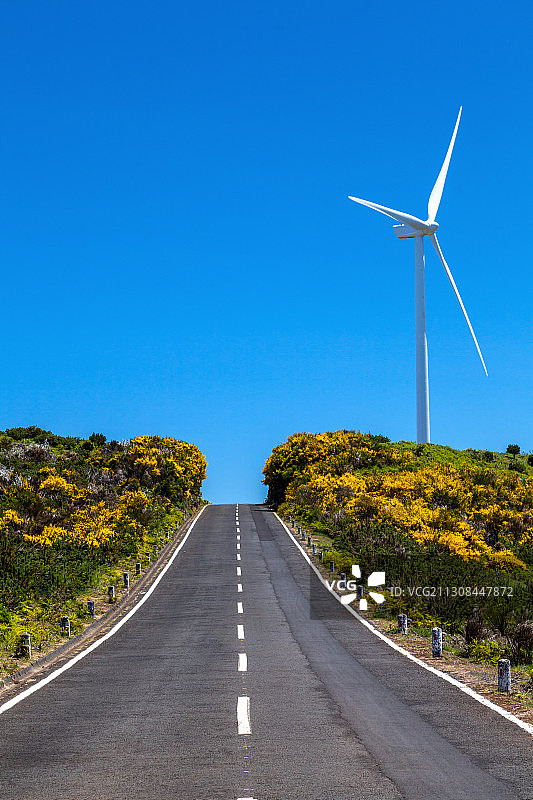 空旷的道路上的风力涡轮机与清澈的蓝天图片素材