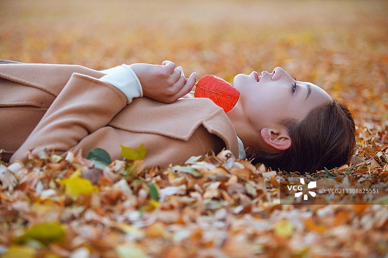 一个年轻女子躺在落叶中图片素材