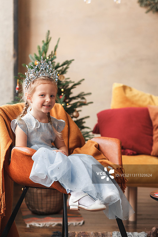 俄罗斯，小女孩在家里的圣诞树旁装扮成公主图片素材