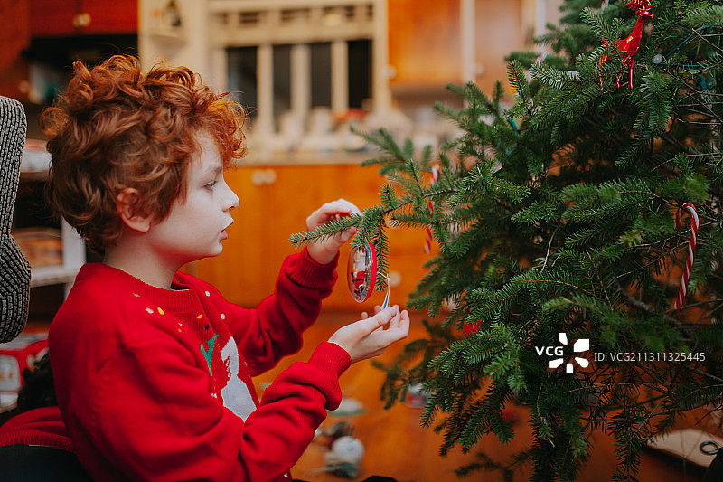 可爱的男孩在家里装饰圣诞树，维多利亚，不列颠哥伦比亚，加拿大图片素材