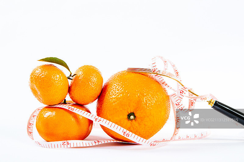 皮尺卷起来的三个橘子和一个橙子图片素材