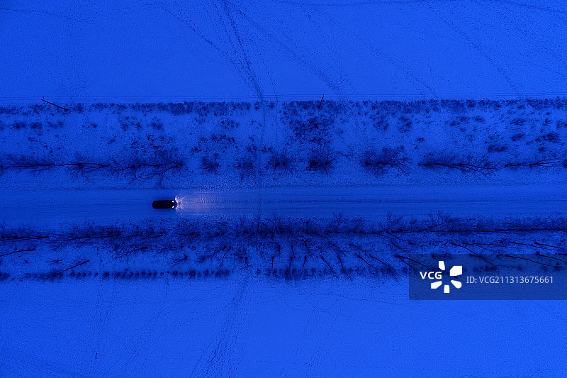 呼伦贝尔一辆汽车行驶在雪夜道路上图片素材