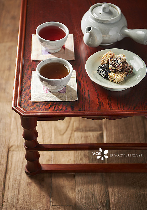 传统茶和甜糯米泡芙放在盘子旁边的茶壶在木桌上图片素材