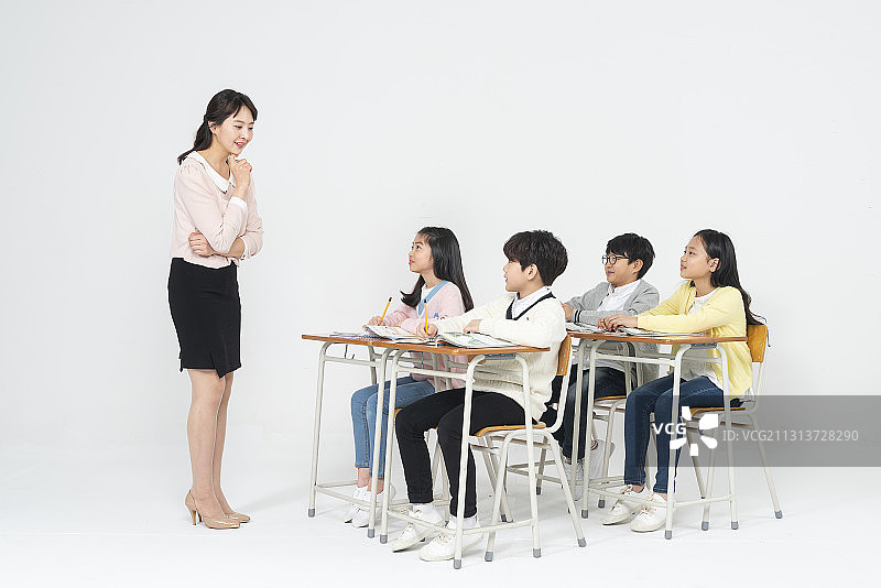老师和四个孩子坐在课桌旁学习图片素材