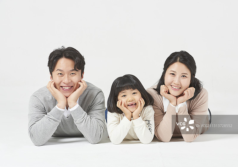 三名家庭成员趴在白色的背景上，双手托着下巴微笑图片素材