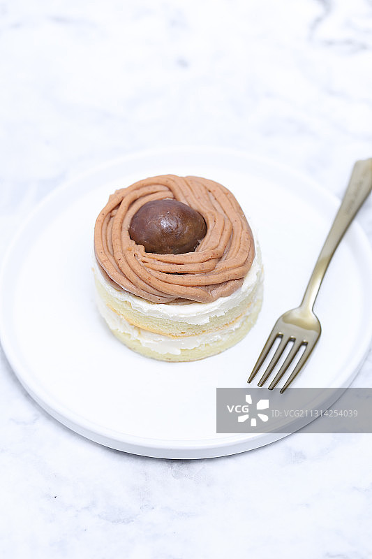 一个放在白色大理石背景上的栗子奶油蛋糕图片素材