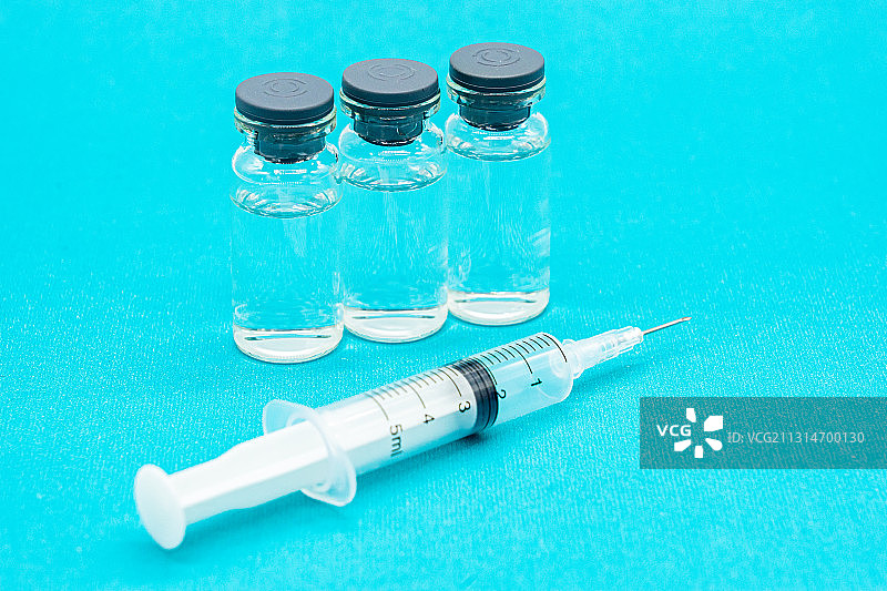 蓝色背景下的疫苗和注射器图片素材