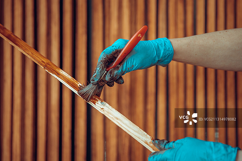 裁剪的人的手正在刷一块木头上的污渍图片素材