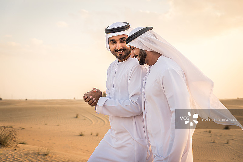 阿拉伯联合酋长国迪拜，两个阿拉伯人在沙漠中亲密无间图片素材