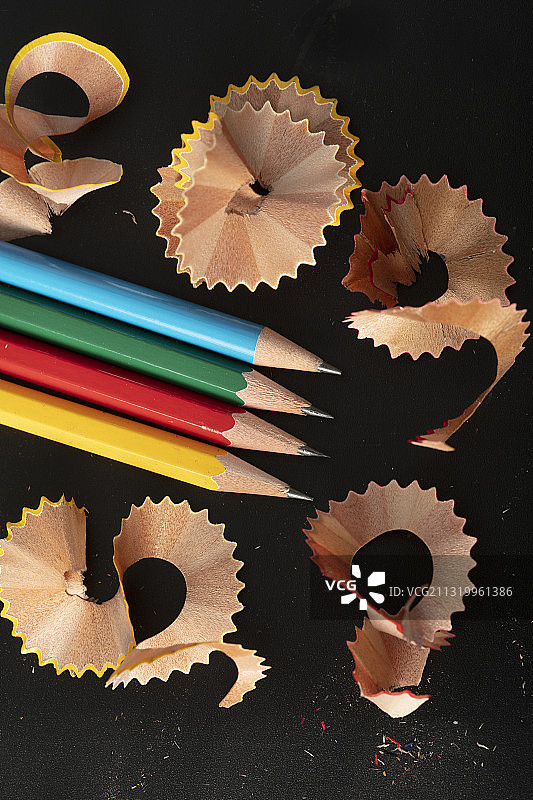 彩虹铅笔和铅笔刨花在纯黑色的背景图片素材
