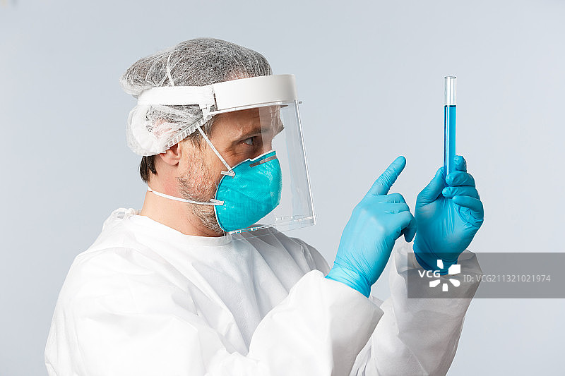 身穿白色外科手术服，戴着蓝色手套的男医生站在白色背景下图片素材