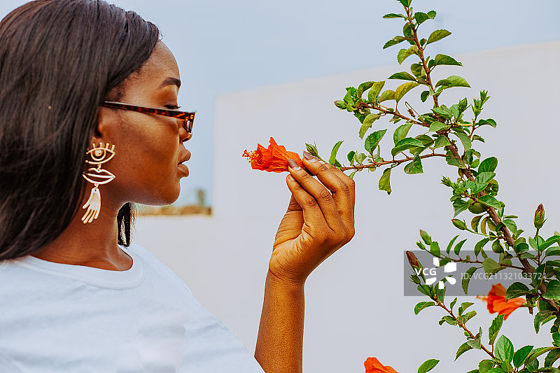 加纳特马，一名年轻的非洲妇女站在鲜花附近的户外肖像图片素材