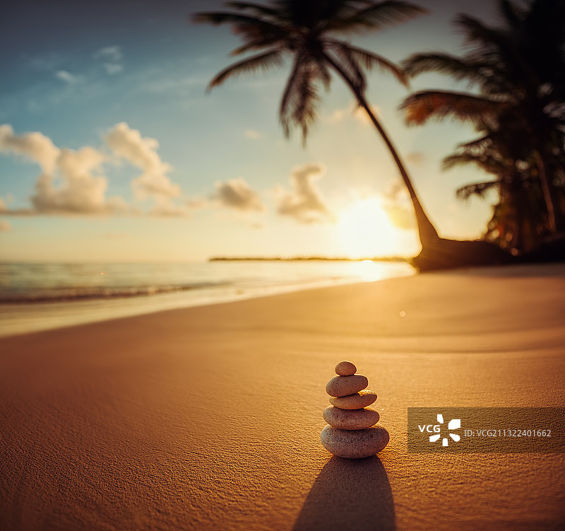 日落时海滩上堆叠的鹅卵石的特写图片素材
