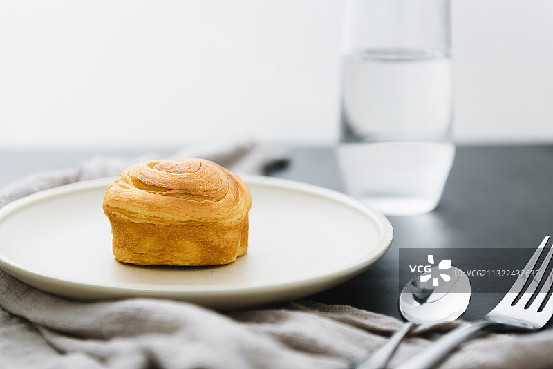 早上窗户边上桌面上的早餐，美味可口的面包和一杯水图片素材