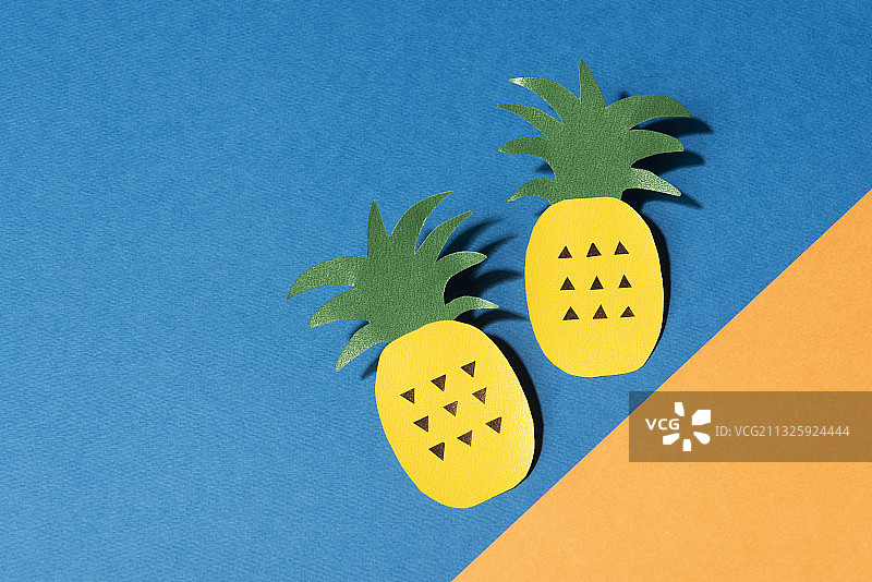 蓝色和黄色背景上的两个菠萝的纸艺术图片素材