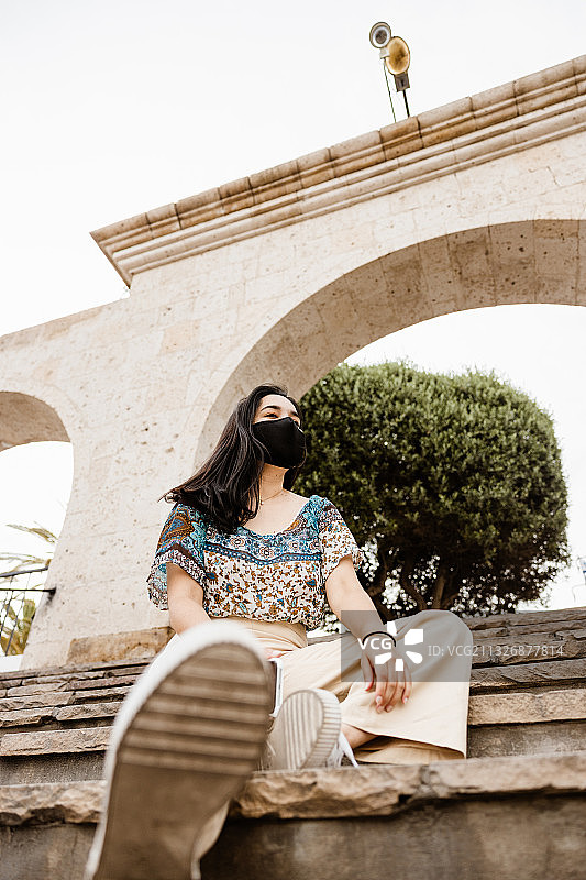 秘鲁阿雷基帕，一名戴着口罩坐在旧建筑上的妇女图片素材