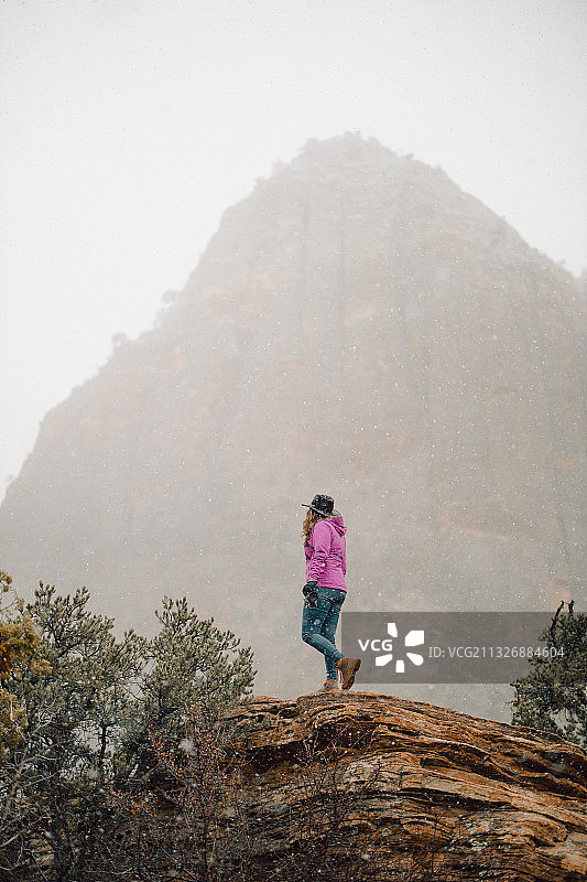 美国犹他州锡安国家公园，站在天空下的高山上的爱冒险的女人图片素材